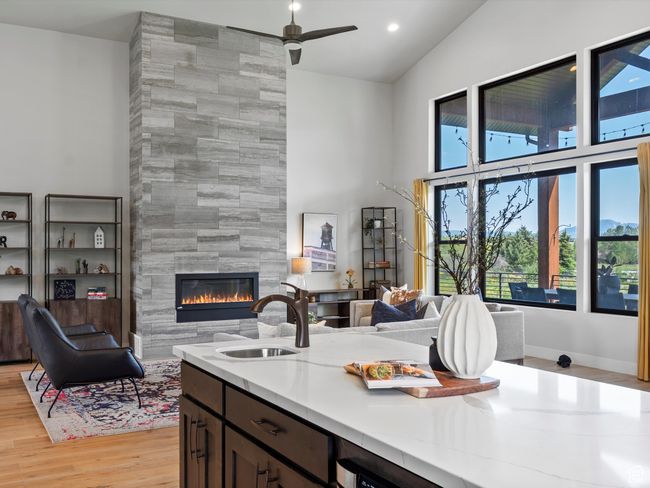 Kitchen featuring a sink, high vaulted ceiling, open floor plan, a fireplace, and light wood-style floors | Image 14