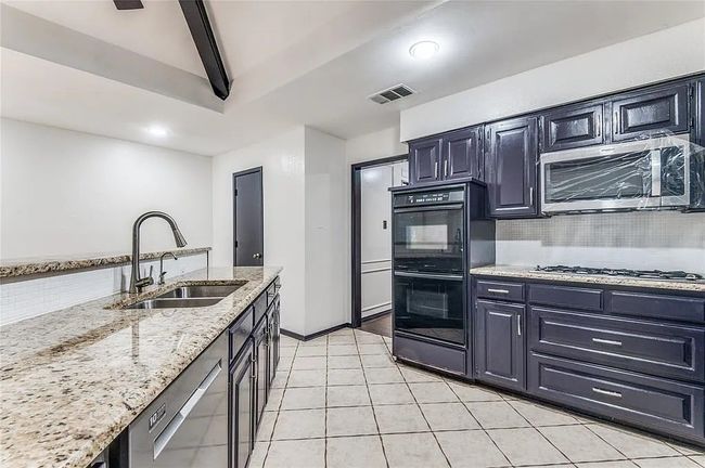 Kitchen featuring light stone counters, stainless steel appliances, a sink, visible vents, and tasteful backsplash | Image 10