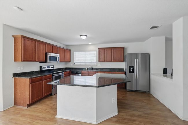 Kitchen with appliances with stainless steel finishes, a sink, light wood-type flooring, and a center island | Image 6