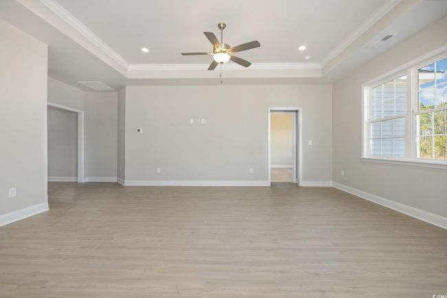 Unfurnished room with a raised ceiling, ceiling fan, light hardwood / wood-style flooring, and crown molding | Image 6