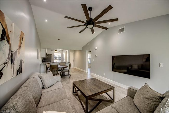 Living room with ceiling fan, vaulted ceiling, and light wood-type flooring | Image 5