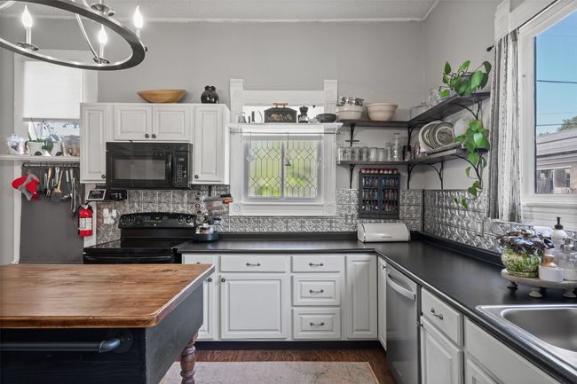Kitchen with black appliances, dark wood finished floors, open shelves, white cabinetry, and ornamental molding | Image 15