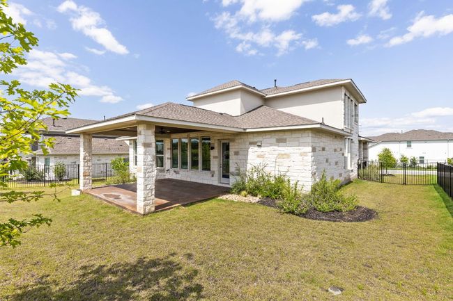 Rear view of house with a patio, stone siding, and a shingled roof | Image 33