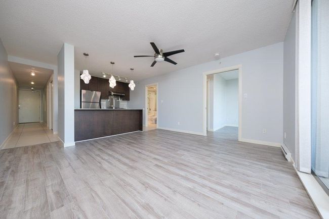 Unfurnished living room with light wood finished floors, baseboards, ceiling fan, and a textured ceiling | Image 9