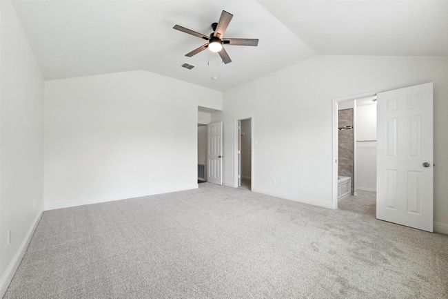 Unfurnished bedroom featuring lofted ceiling, light carpet, a ceiling fan, and ensuite bathroom | Image 18