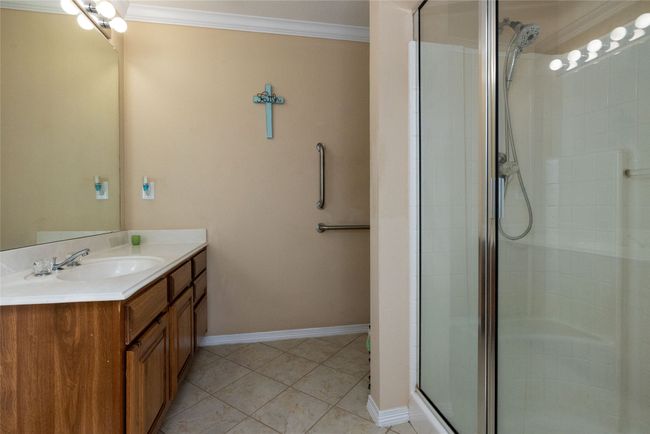 Bathroom featuring baseboards, tile patterned flooring, a shower stall, crown molding, and vanity | Image 25