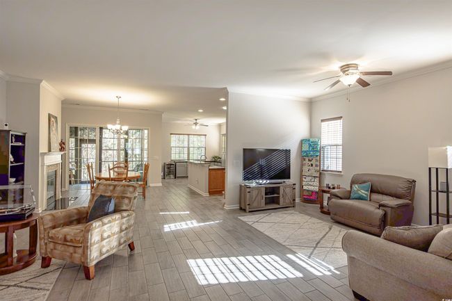 Living room featuring ceiling fan with notable chandelier, light wood-type flooring, and ornamental molding | Image 14
