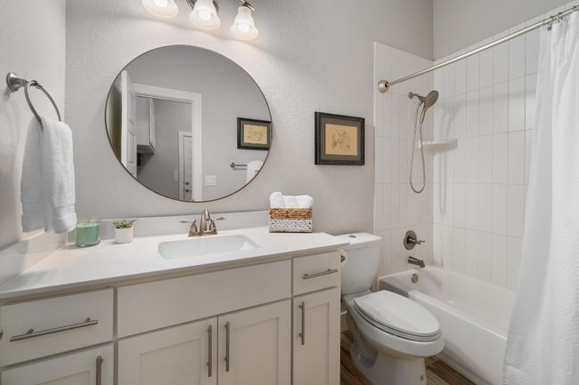 Downstairs full bathroom featuring shower / tub combo with curtain, toilet, and vanity | Image 14