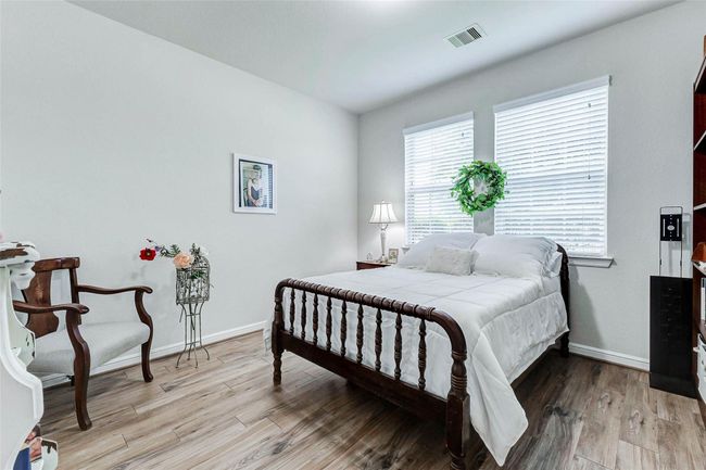 Guests will appreciate this inviting secondary bedroom, featuring neutral tile floors, tasteful decorator paint, and two windows that fill the room with natural light. | Image 20