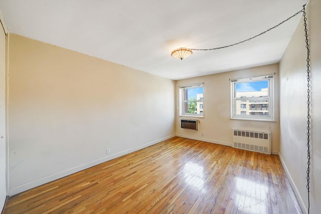 Empty room featuring radiator, light wood-style floors, baseboards, and a wall mounted AC | Image 9