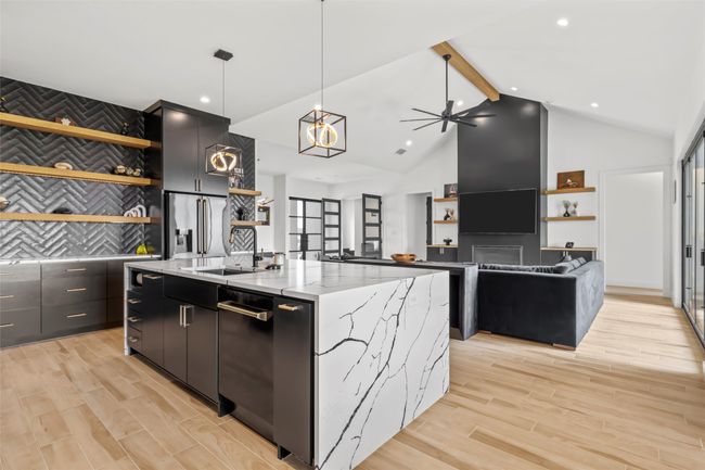 Kitchen featuring open shelves, a sink, dark cabinets, dishwashing machine, and an island with sink | Image 14