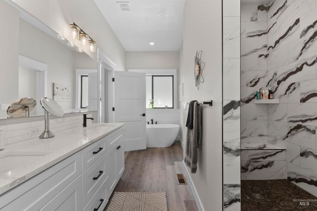 Bathroom with a freestanding tub, double vanity, a walk in shower, wood finished floors, and decorative backsplash | Image 26