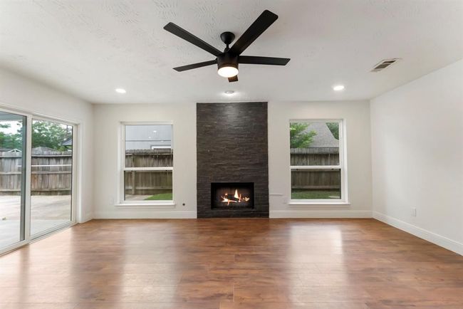Den features stunning gas log fireplace with slate stone focal wall. Entry to covered patio and backyard with views overlooking the pool. | Image 13