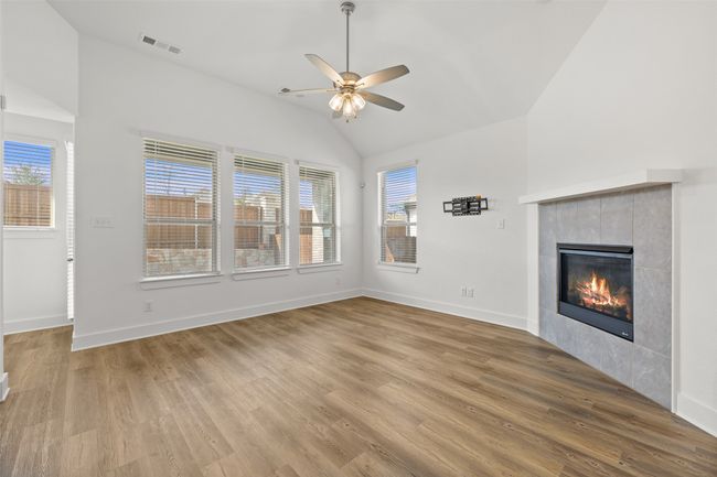 Unfurnished living room featuring wood finished floors, a healthy amount of sunlight, ceiling fan, and visible vents | Image 4