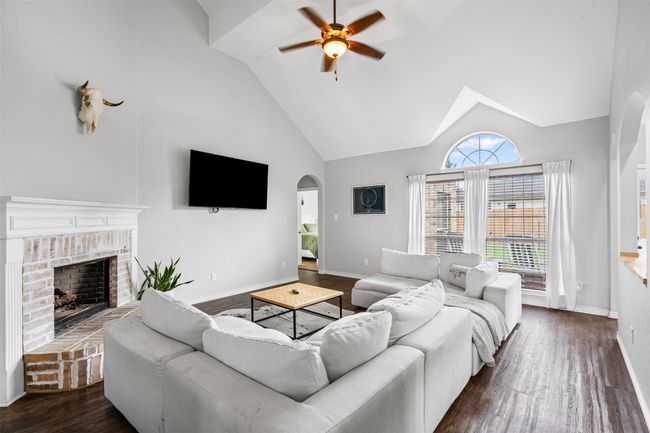 Living room with a ceiling fan, arched walkways, laminate floors, a brick gas fireplace, and high vaulted ceiling | Image 17
