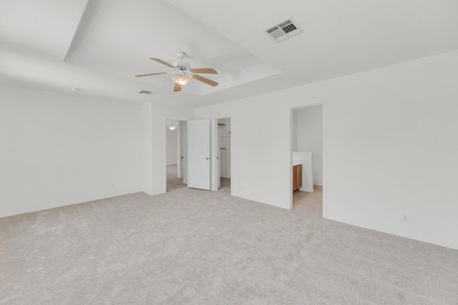 Unfurnished bedroom featuring a tray ceiling, visible vents, light colored carpet, and a walk in closet | Image 15