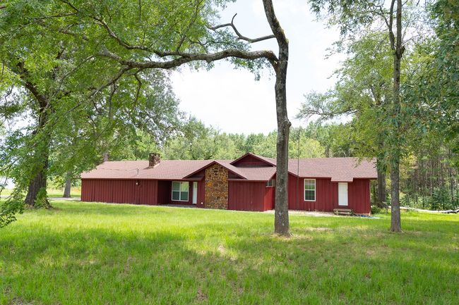 Single story home with a chimney, a front yard, stone siding, and a shingled roof | Image 5