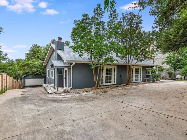 View of front of property with concrete driveway, a chimney, metal roof, an outbuilding, and fence | Image 24