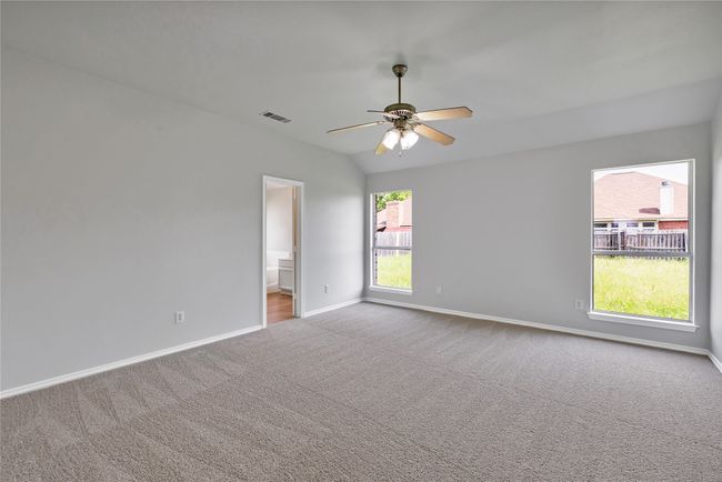 Carpeted empty room with baseboards, a ceiling fan, and lofted ceiling | Image 15