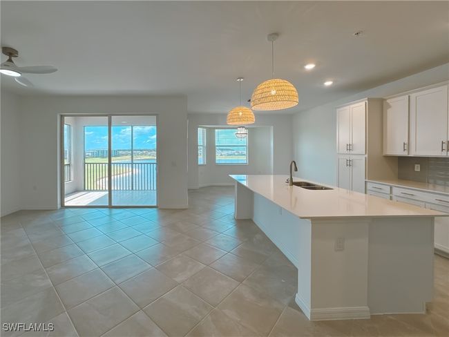 Kitchen featuring a sink, baseboards, light countertops, a kitchen island with sink, and recessed lighting | Image 9