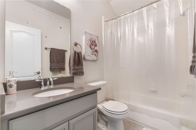 The modern design bathroom with sleek gray countertops, an under-mount sink, and a large mirror. | Image 32