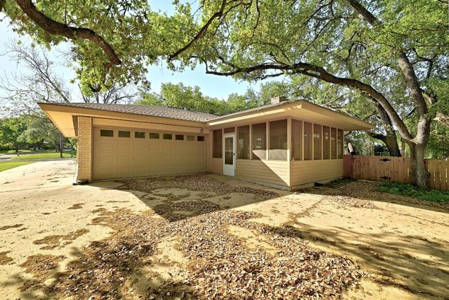View of front facade with concrete driveway, a sunroom, fence, and a garage | Image 29