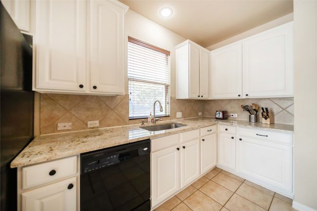 Kitchen featuring black appliances, decorative backsplash, light stone counters, light tile patterned floors, and recessed lighting | Image 14