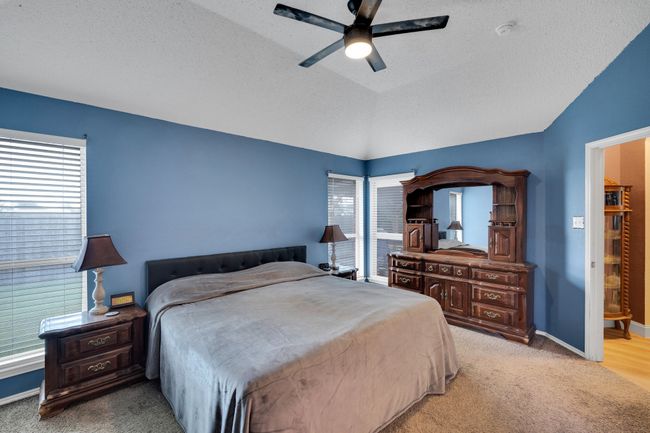 Bedroom featuring multiple windows, light carpet, a textured ceiling, lofted ceiling, and ceiling fan | Image 26