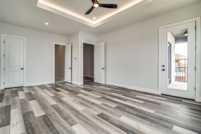 Empty room with wood-type flooring, ceiling fan, and a raised ceiling | Image 15