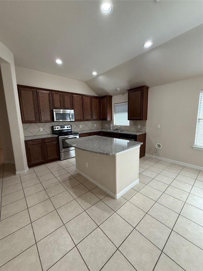 Kitchen with a center island, range, decorative backsplash, and lofted ceiling | Image 6