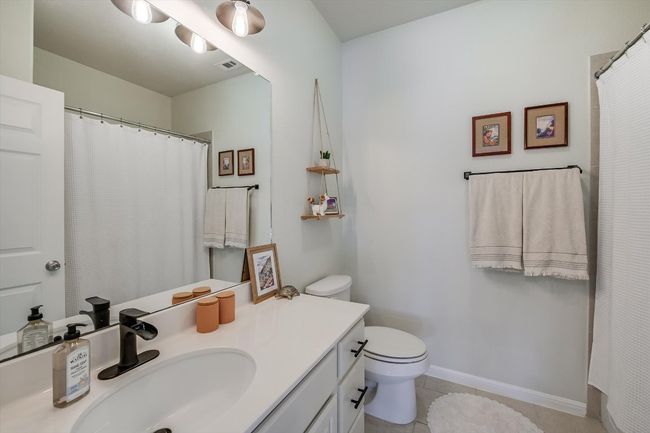 Bathroom with vanity, toilet, tile patterned flooring, curtained shower, and baseboards | Image 22
