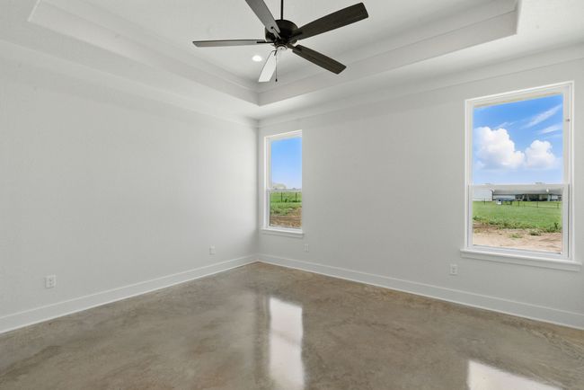 Spare room featuring a raised ceiling, concrete flooring, baseboards, recessed lighting, and a ceiling fan | Image 11