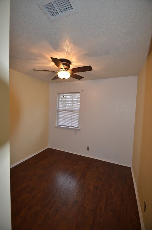 Unfurnished room featuring dark wood finished floors, a textured ceiling, ceiling fan, and baseboards | Image 6