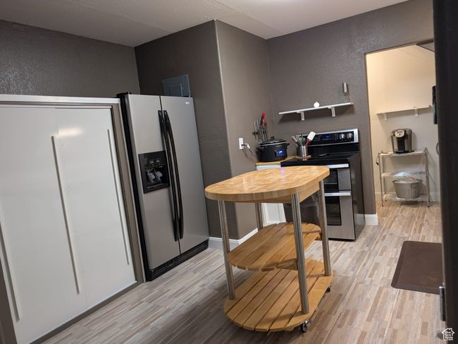 Kitchen featuring baseboards, a textured wall, light wood-style flooring, and stainless steel appliances | Image 14