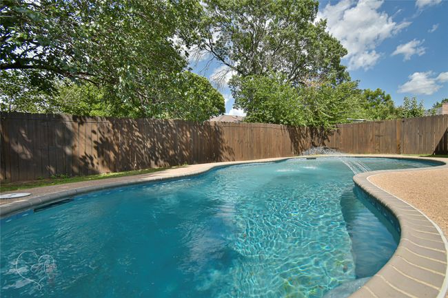 View of swimming pool with a fenced backyard | Image 7