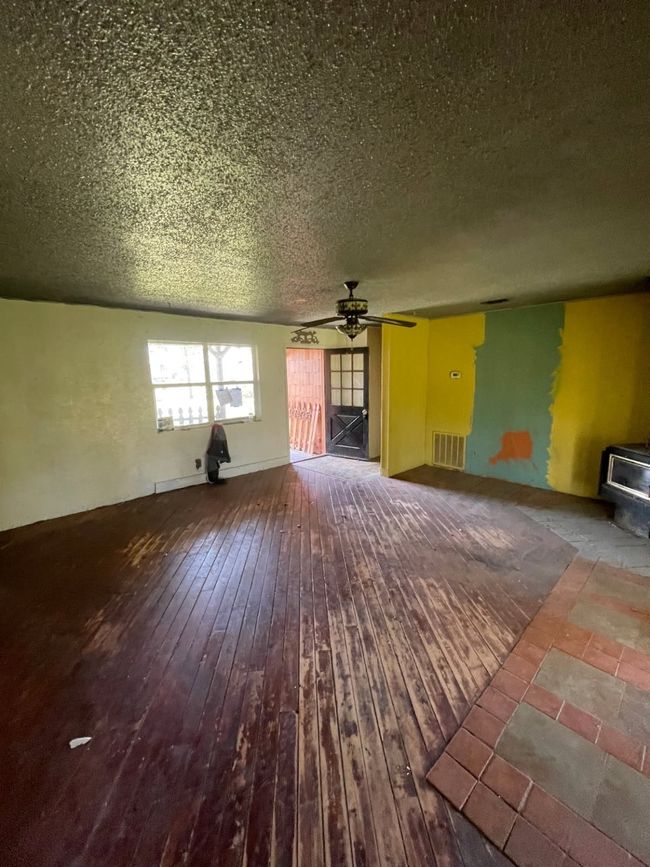 Unfurnished living room featuring a wood stove, hardwood / wood-style floors, a textured ceiling, ceiling fan, and visible vents | Image 17