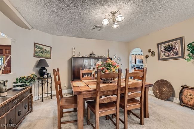 Dining room with light carpet, arched walkways, visible vents, and a notable chandelier | Image 9