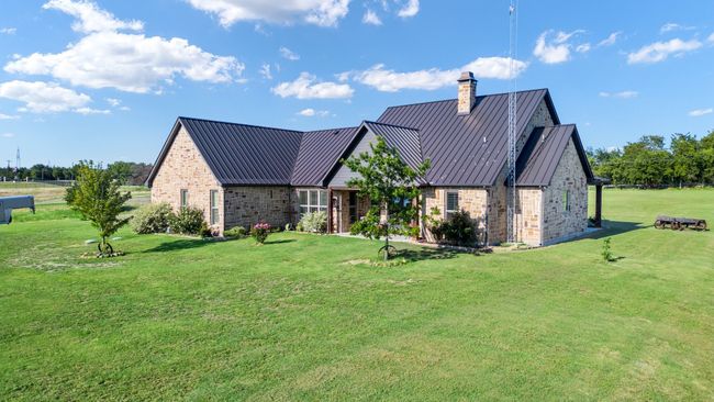 View of front facade with a front lawn, a chimney, brick siding, a standing seam roof, and a metal roof | Image 6