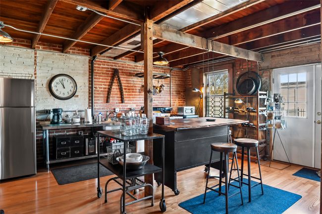 Bar featuring freestanding refrigerator, beam ceiling, brick wall, and wood finished floors | Image 14