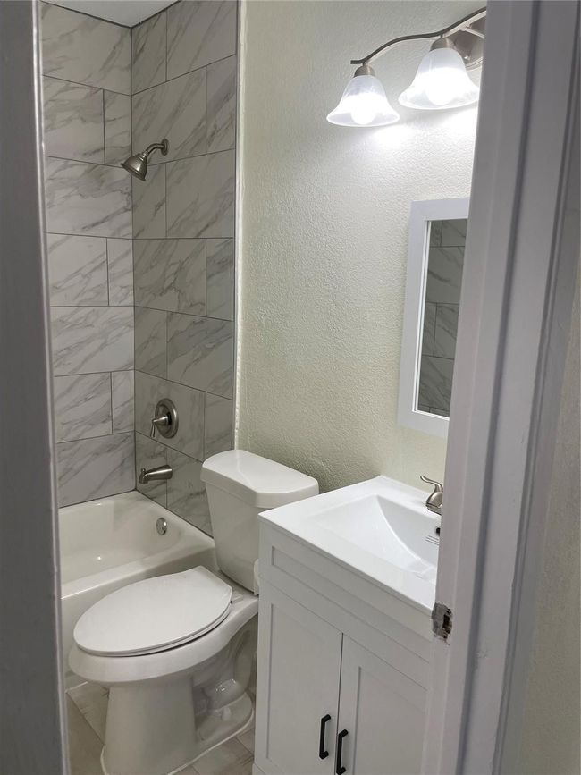 Full bathroom with vanity, shower / washtub combination, toilet, and a textured wall | Image 8