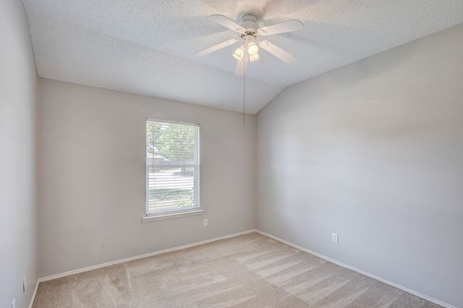 Unfurnished room with light colored carpet, a textured ceiling, ceiling fan, baseboards, and lofted ceiling | Image 23