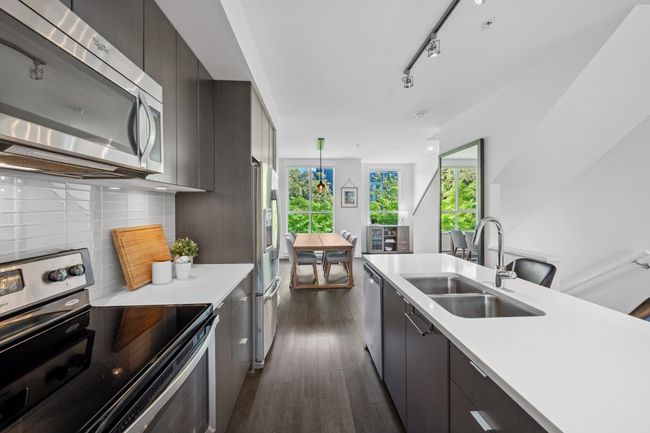 Kitchen featuring stainless steel appliances, a sink, dark wood finished floors, and modern cabinets | Image 7