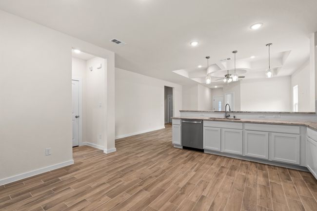 Kitchen featuring stainless steel dishwasher, wood finished floors, a sink, a raised ceiling, and recessed lighting | Image 15