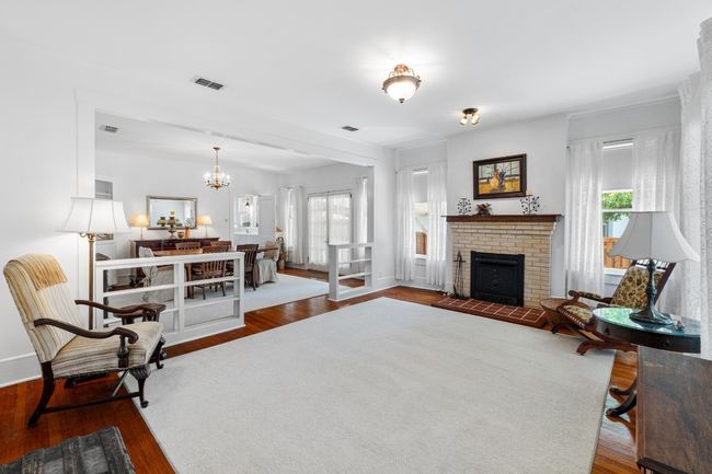 Living area with wood finished floors, a chandelier, and a brick fireplace | Image 5
