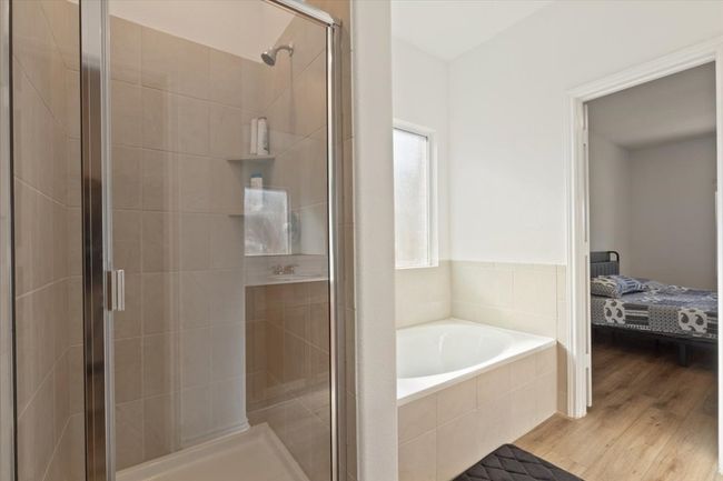 Ensuite bathroom featuring a shower stall, ensuite bathroom, a garden tub, and wood finished floors | Image 9