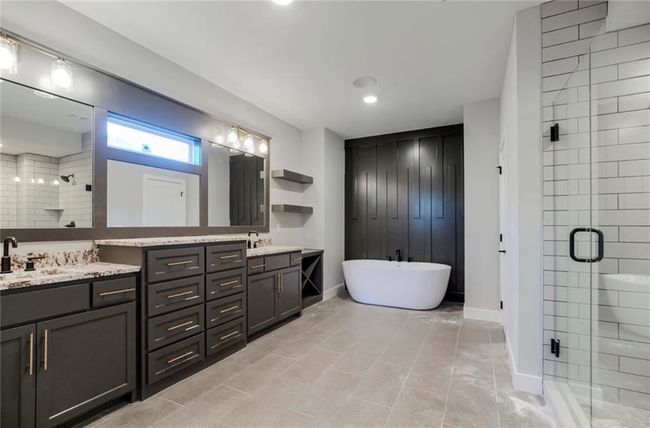 Full bath featuring a shower stall, double vanity, a freestanding bath, baseboards, and recessed lighting | Image 11
