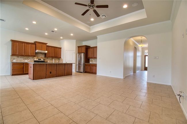 Kitchen featuring arched walkways, open floor plan, a raised ceiling, and freestanding refrigerator | Image 11