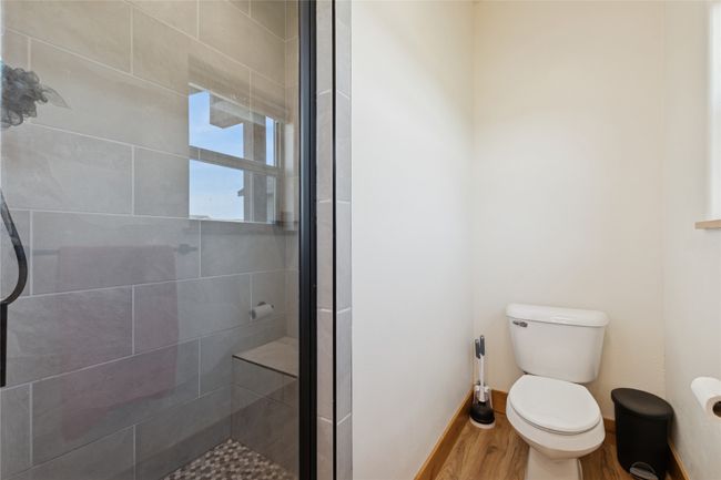 Bathroom featuring toilet, baseboards, a stall shower, and wood finished floors | Image 29