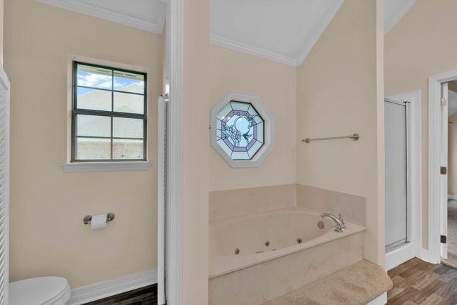 Bathroom featuring crown molding, a shower stall, a tub with jets, and wood finished floors | Image 21