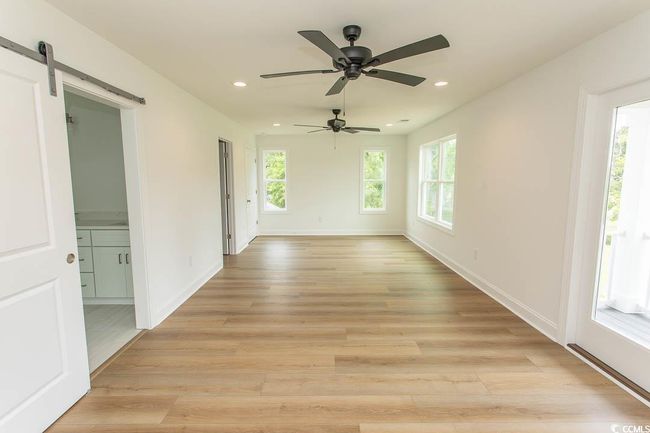 Master room featuring light wood-style flooring, recessed lighting, a barn door, a ceiling fan, and baseboards | Image 24